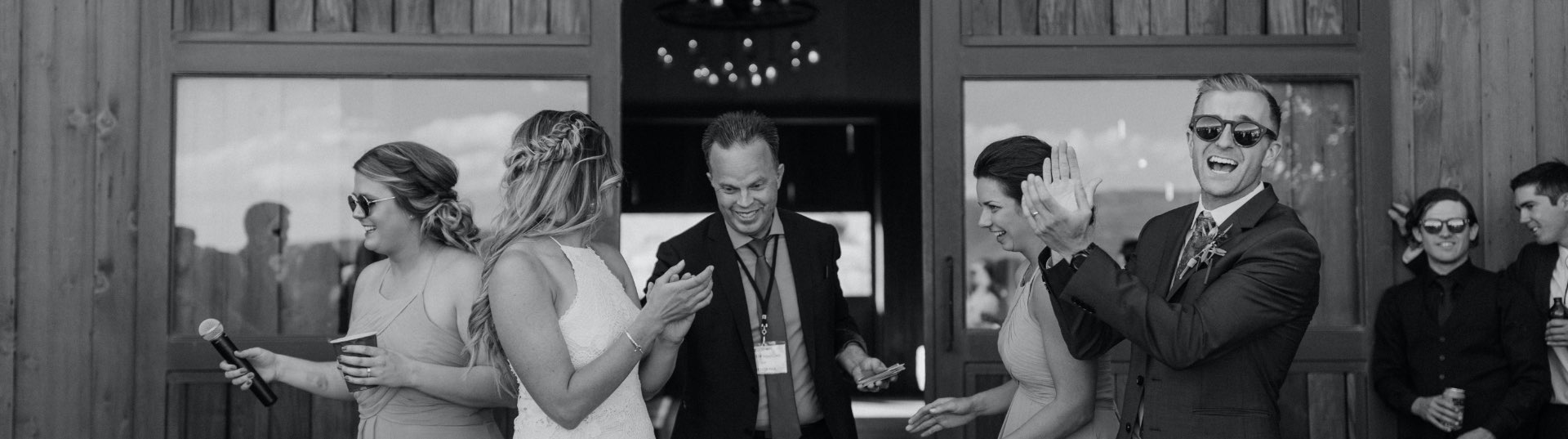 Doug Roy stepping through a large open doorway, being greeted by applauding couples, who are smiling and laughing. Blue overlay.