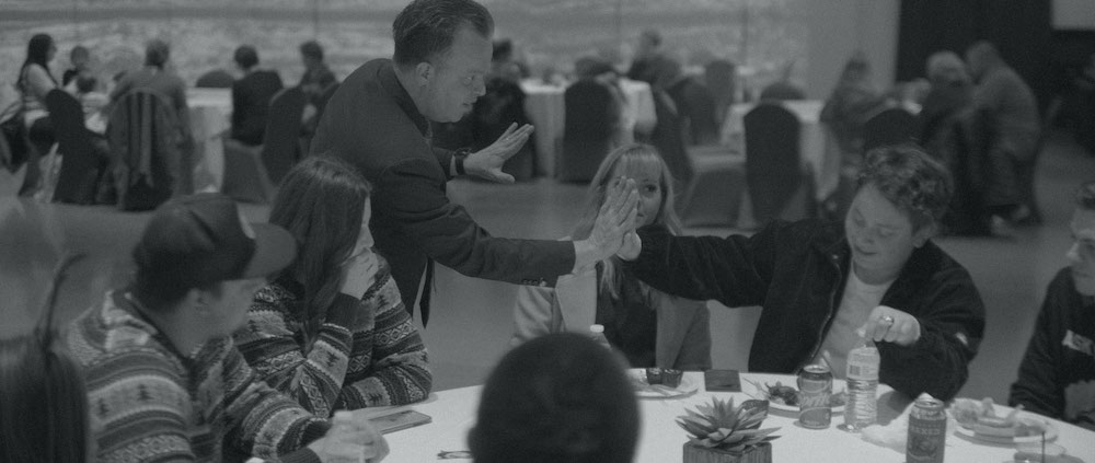 Black and white image of Doug giving a high five to a kid at a party