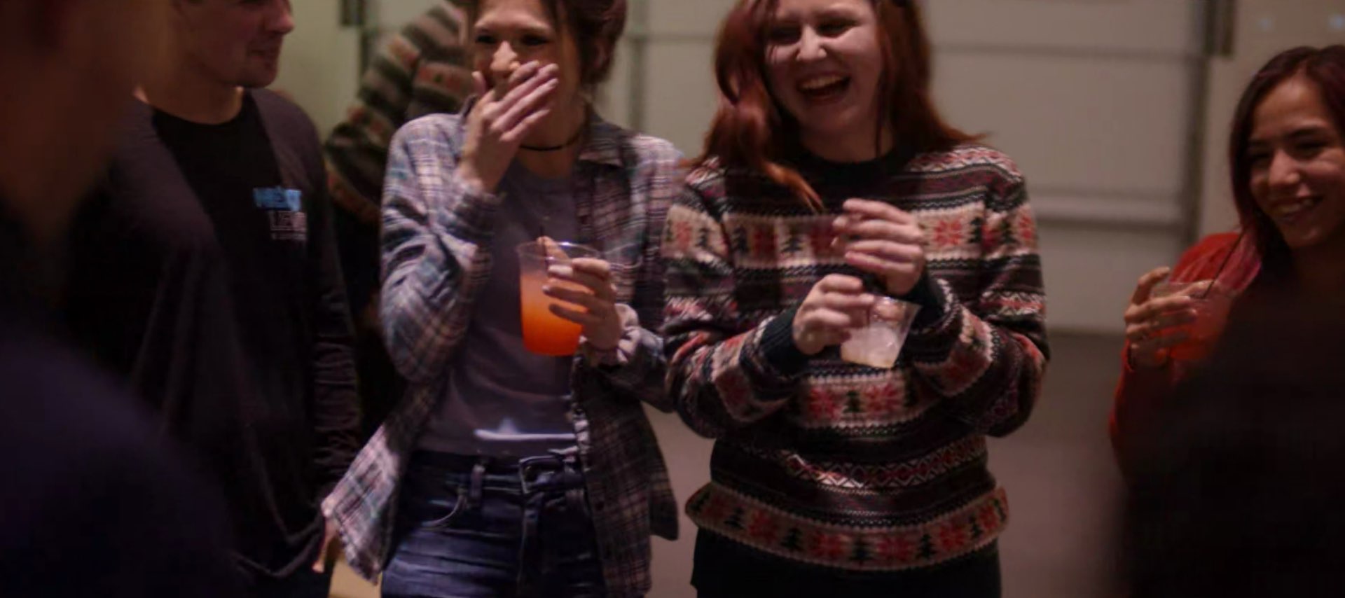 Girls holding drinks are laughing.