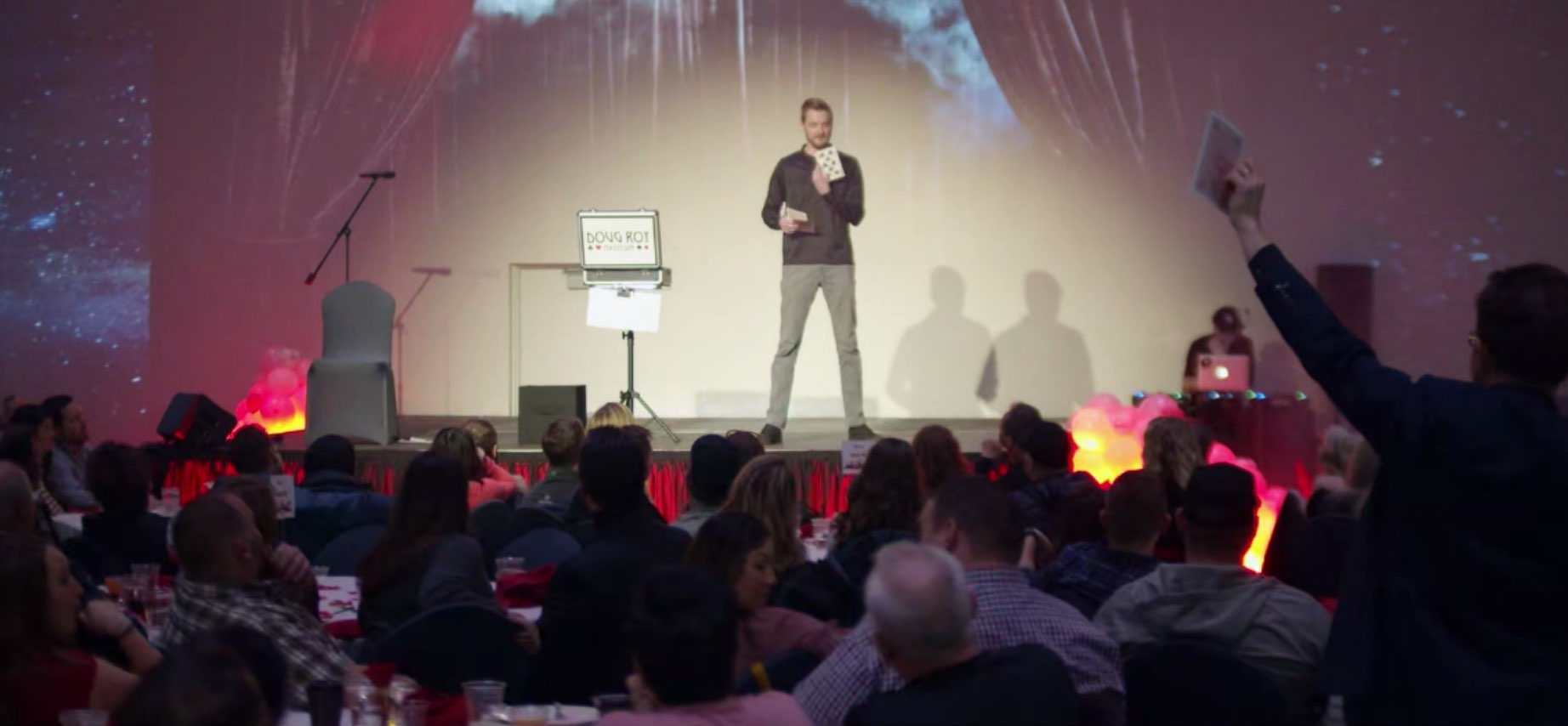 Guy on stage holding a large playing card.