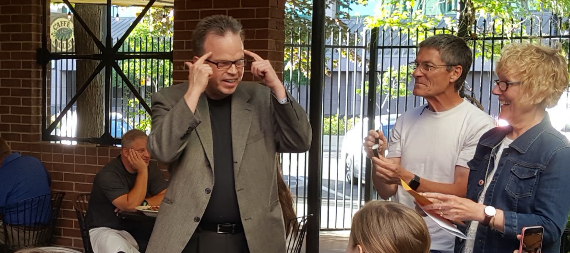 Doug standing with a couple who are holding a watch and an envelope.