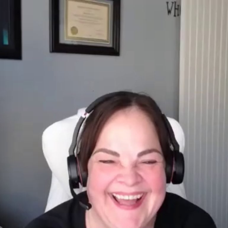 Screen shot of gal wearing headphones laughing.
